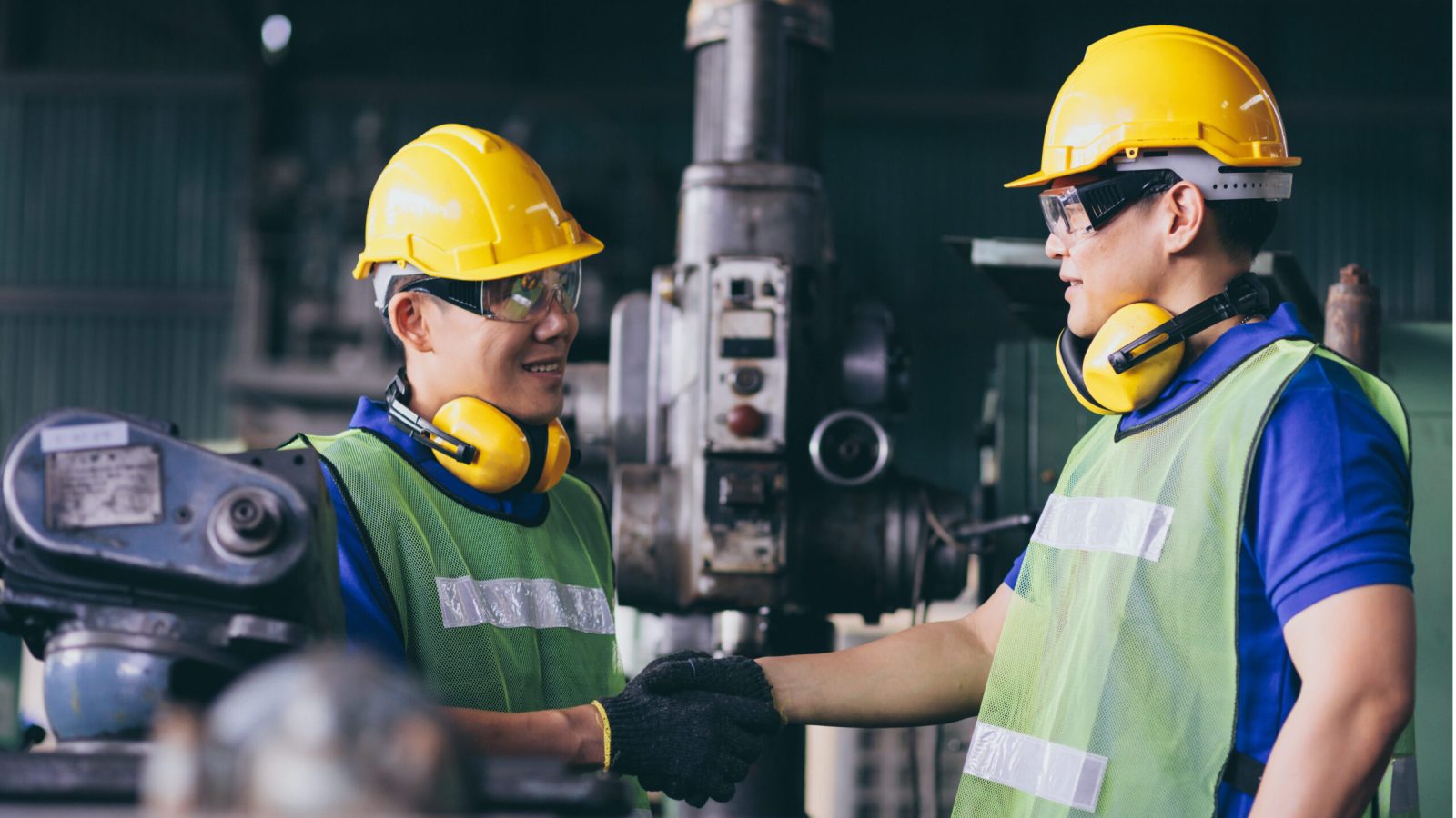 Turner is working on the machine.metal processing.worker works on a lathe.Turner running on the machine. men is wearing a uniform safety vest.