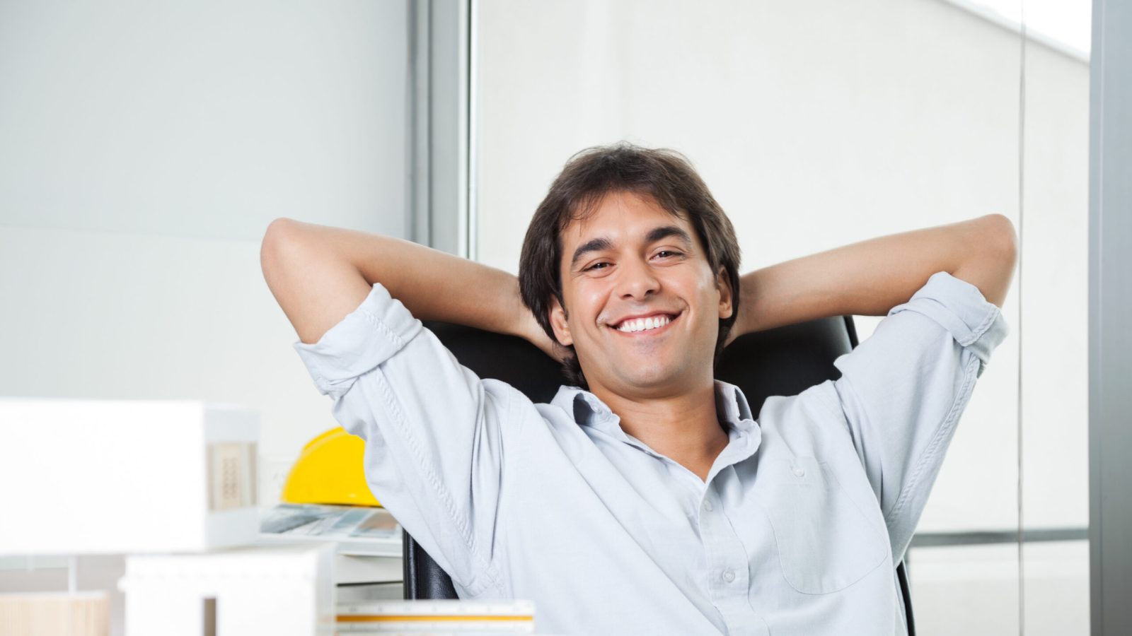 Portrait of a relaxed male architect sitting in chair with hands behind head